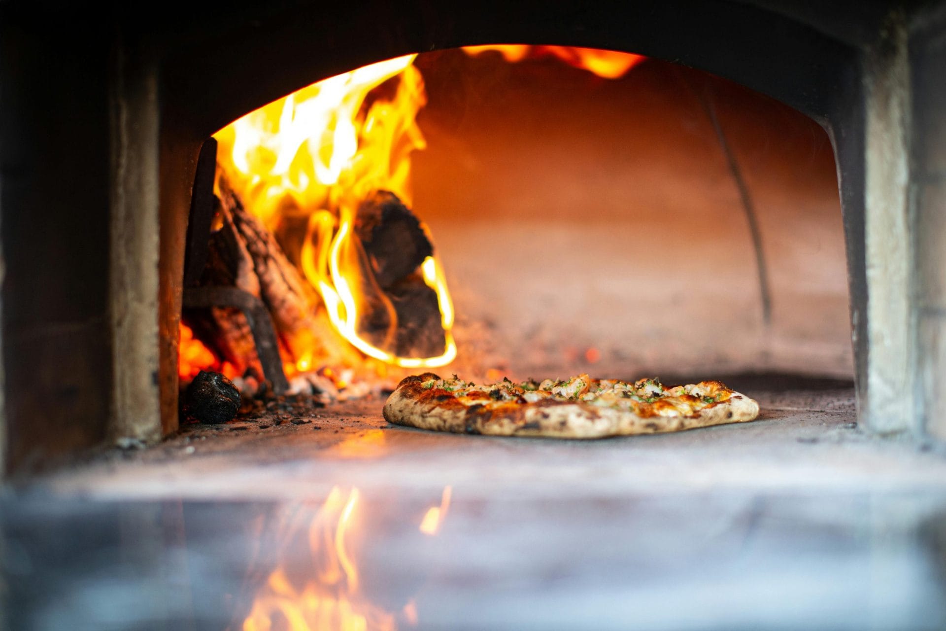 Pizza sortant d'un four à bois avec une croûte parfaitement dorée